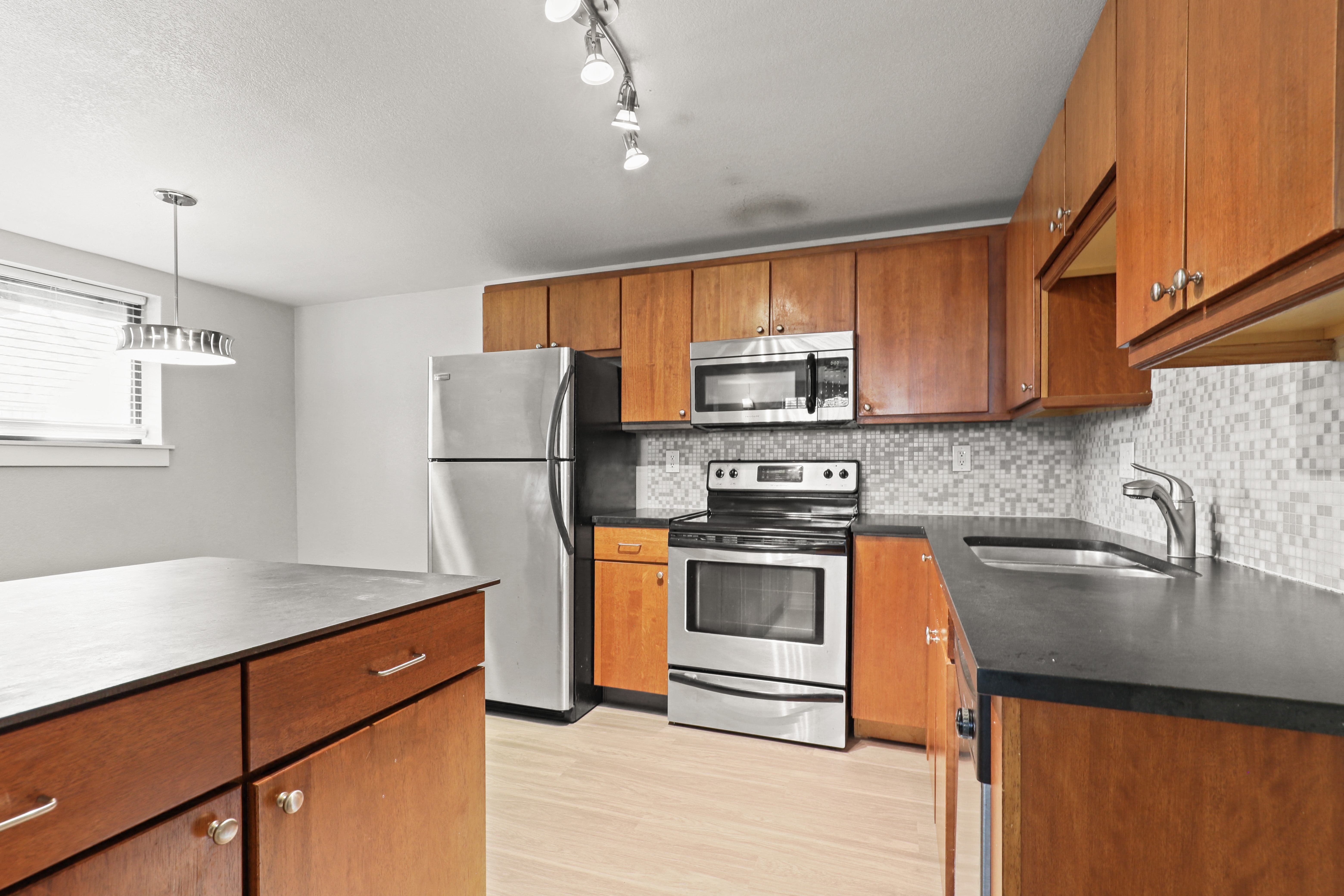 an empty kitchen with wooden cabinets and stainless steel appliances